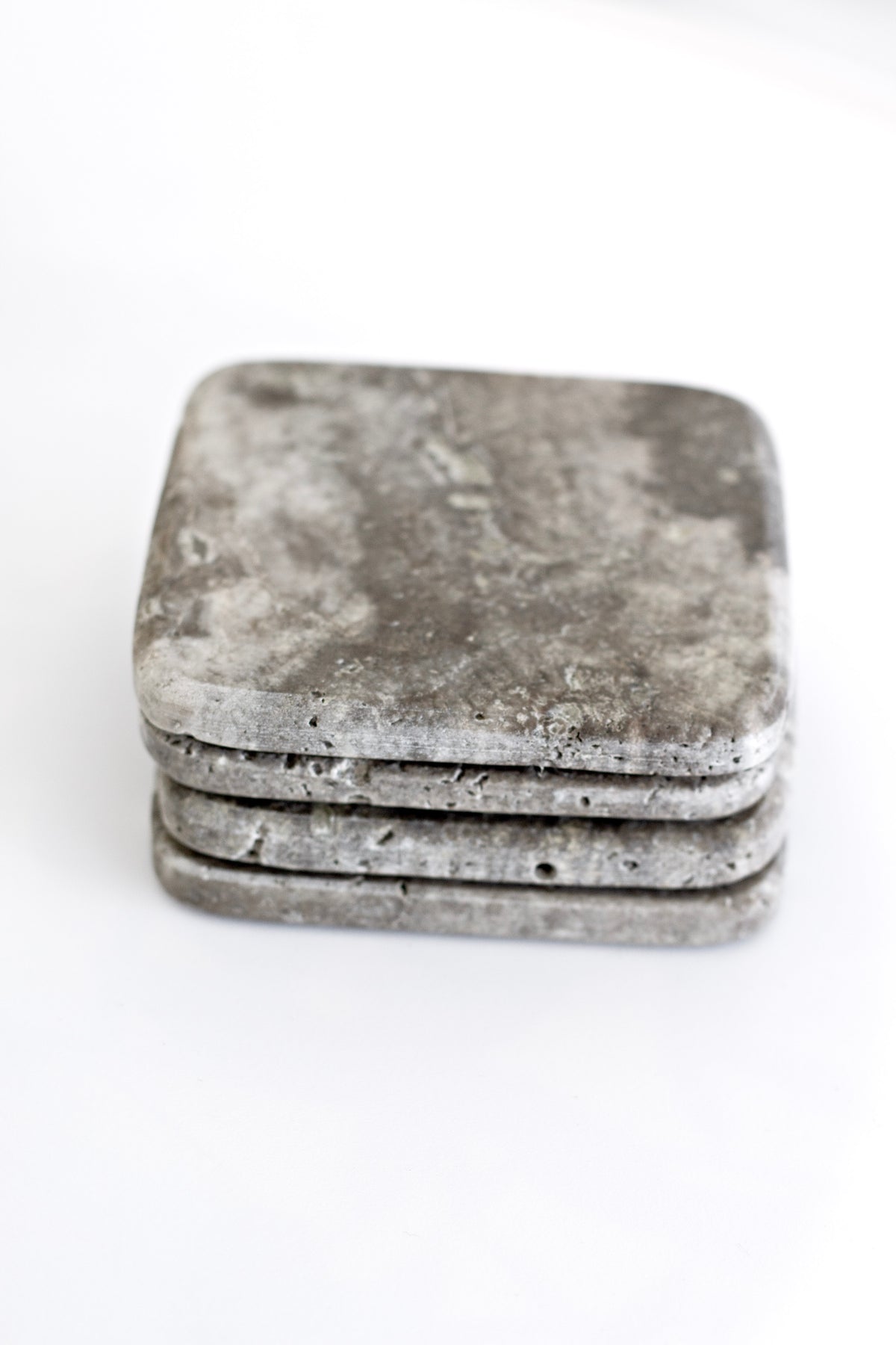 Stack of natural travertine coasters on a white background