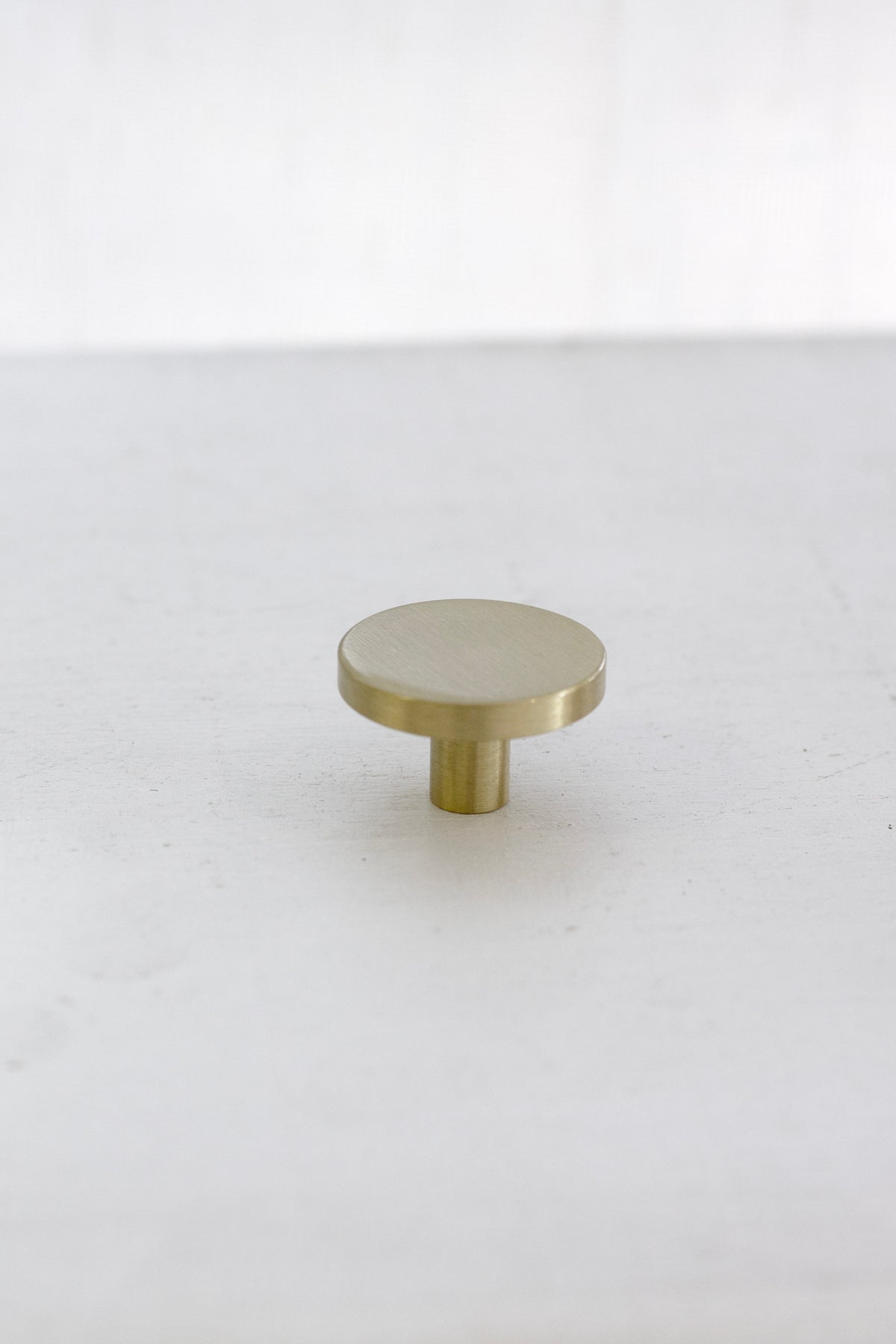 Side view of the brushed gold brass wall hook on a white surface