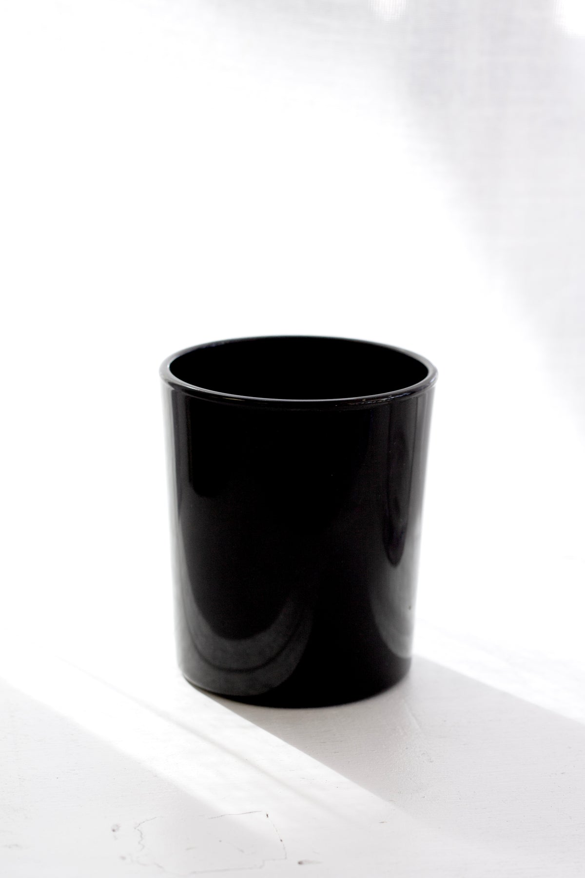 Black glass holder in soft window light, empty