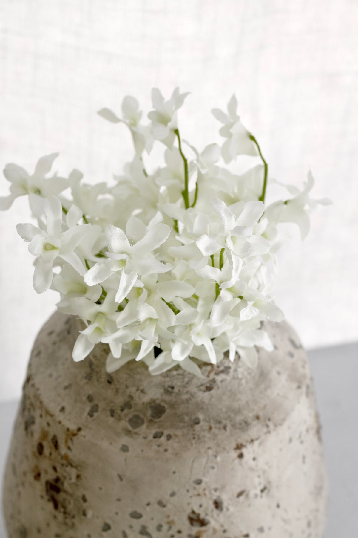 Faux orchids in a speckled stone vase