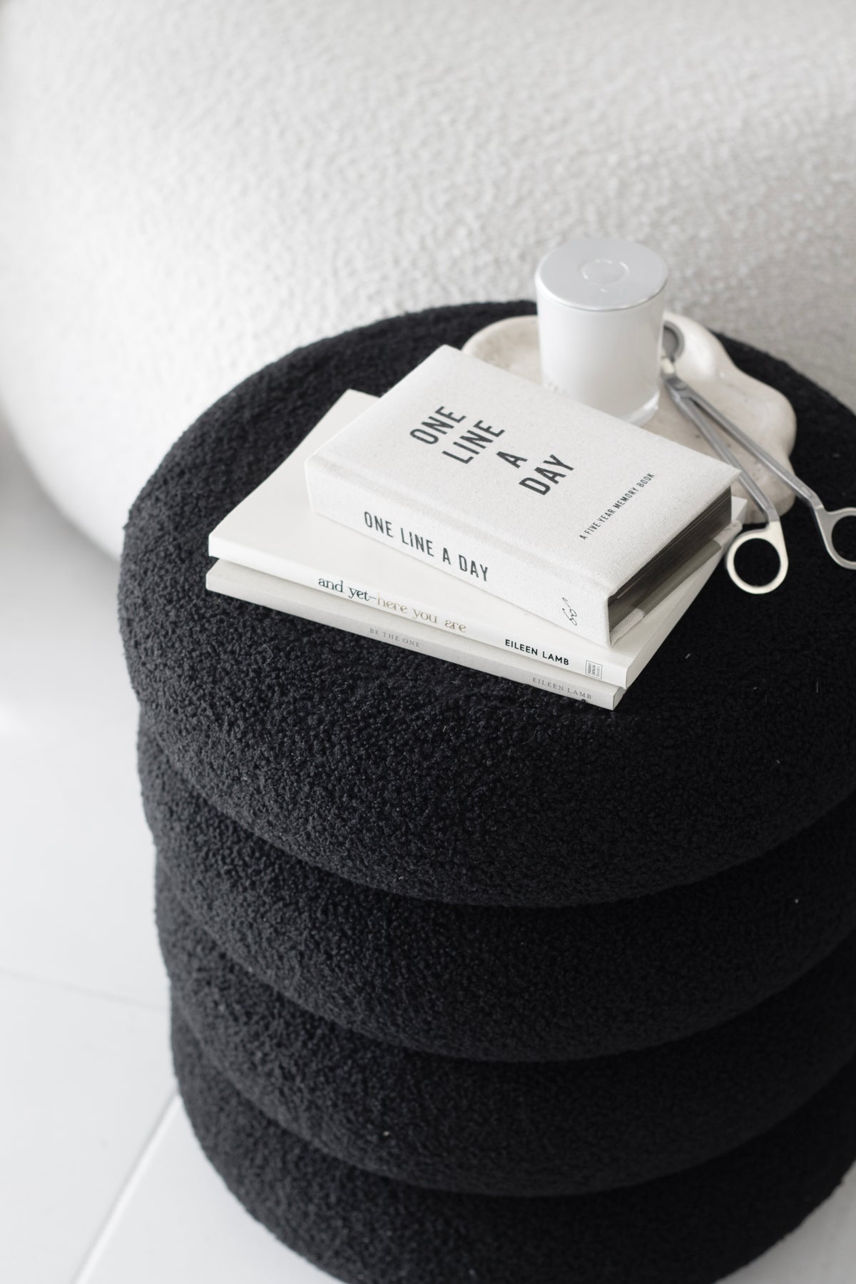 Black tiered ottoman topped with a white book and a small cup