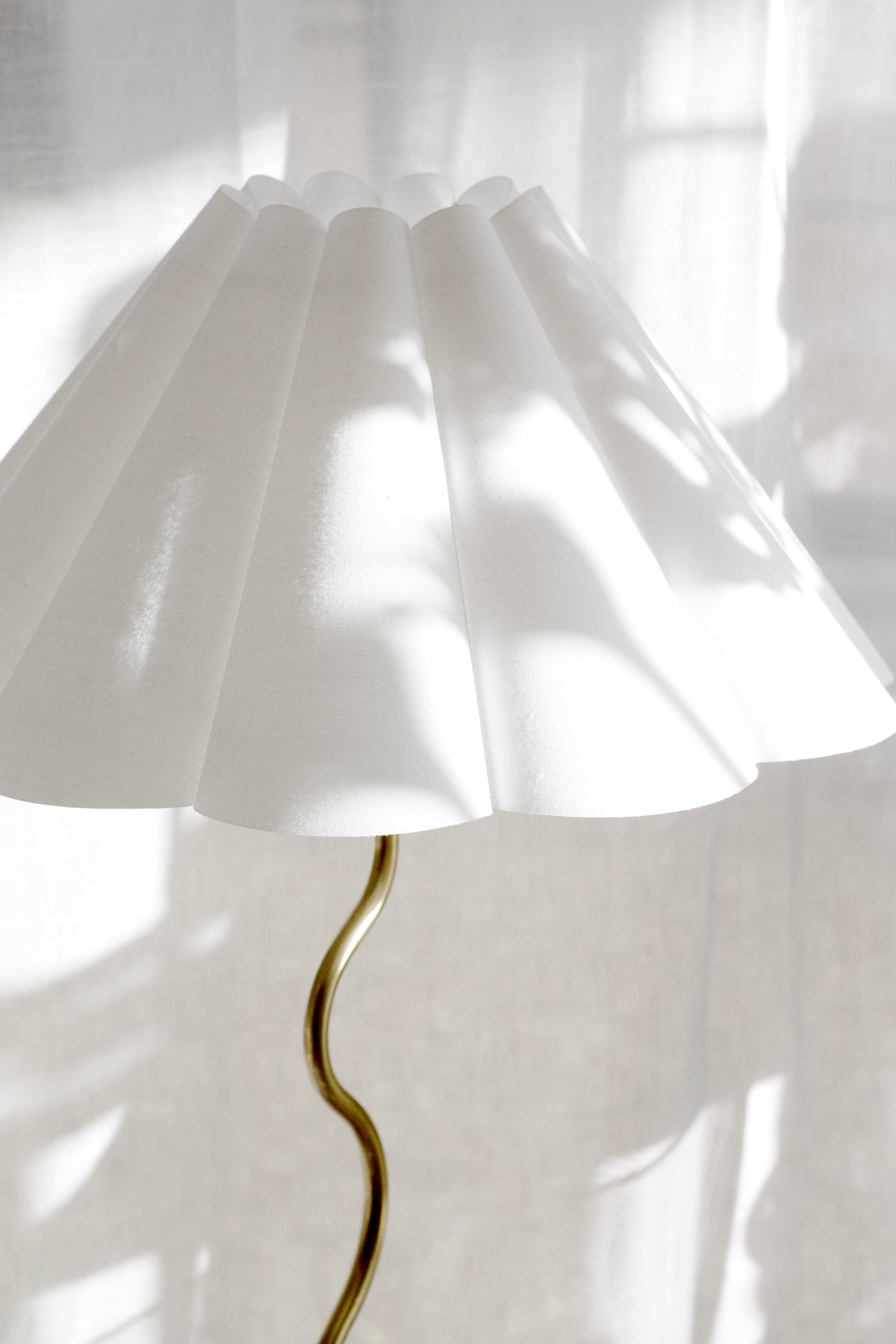 Detail of the pleated off-white fabric shade on the brass Wavy table lamp
