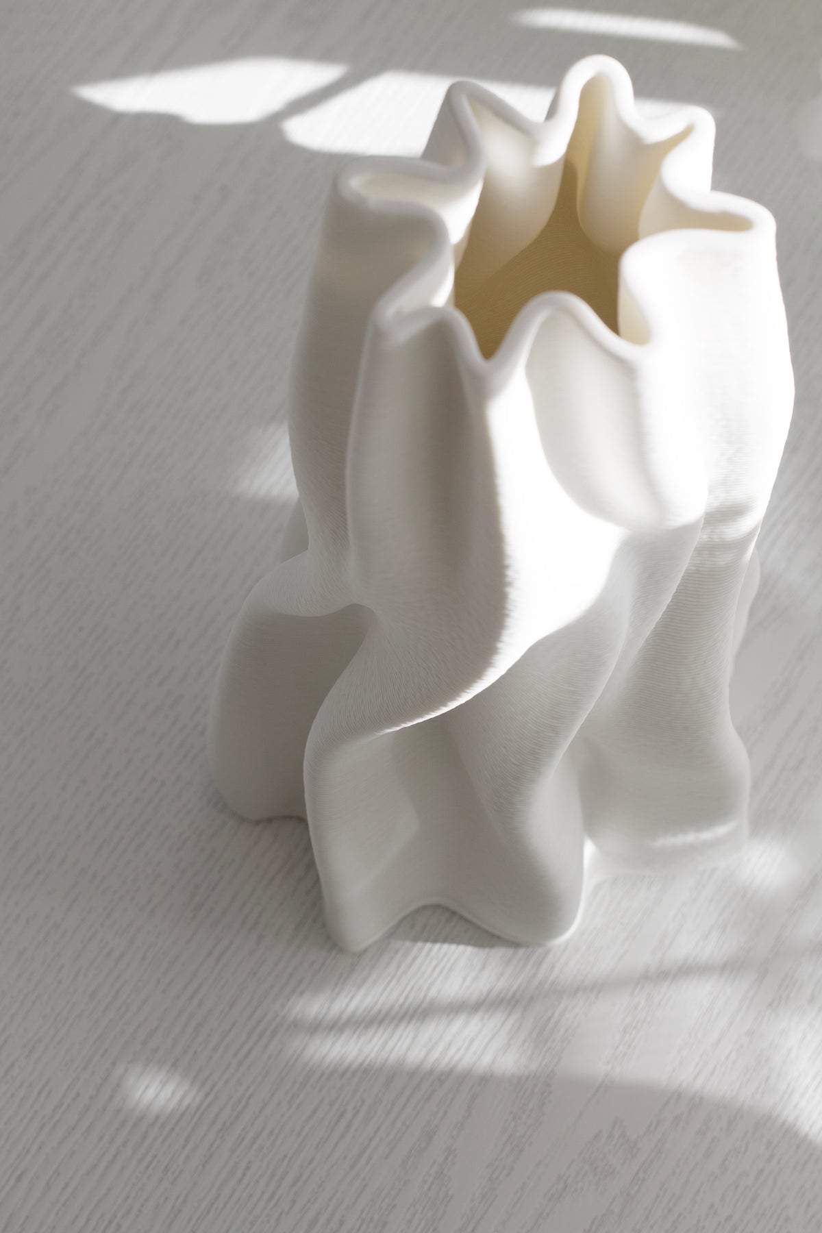 Angled view into the Anouk vase showing its star-shaped opening and wave ridges in soft shadow