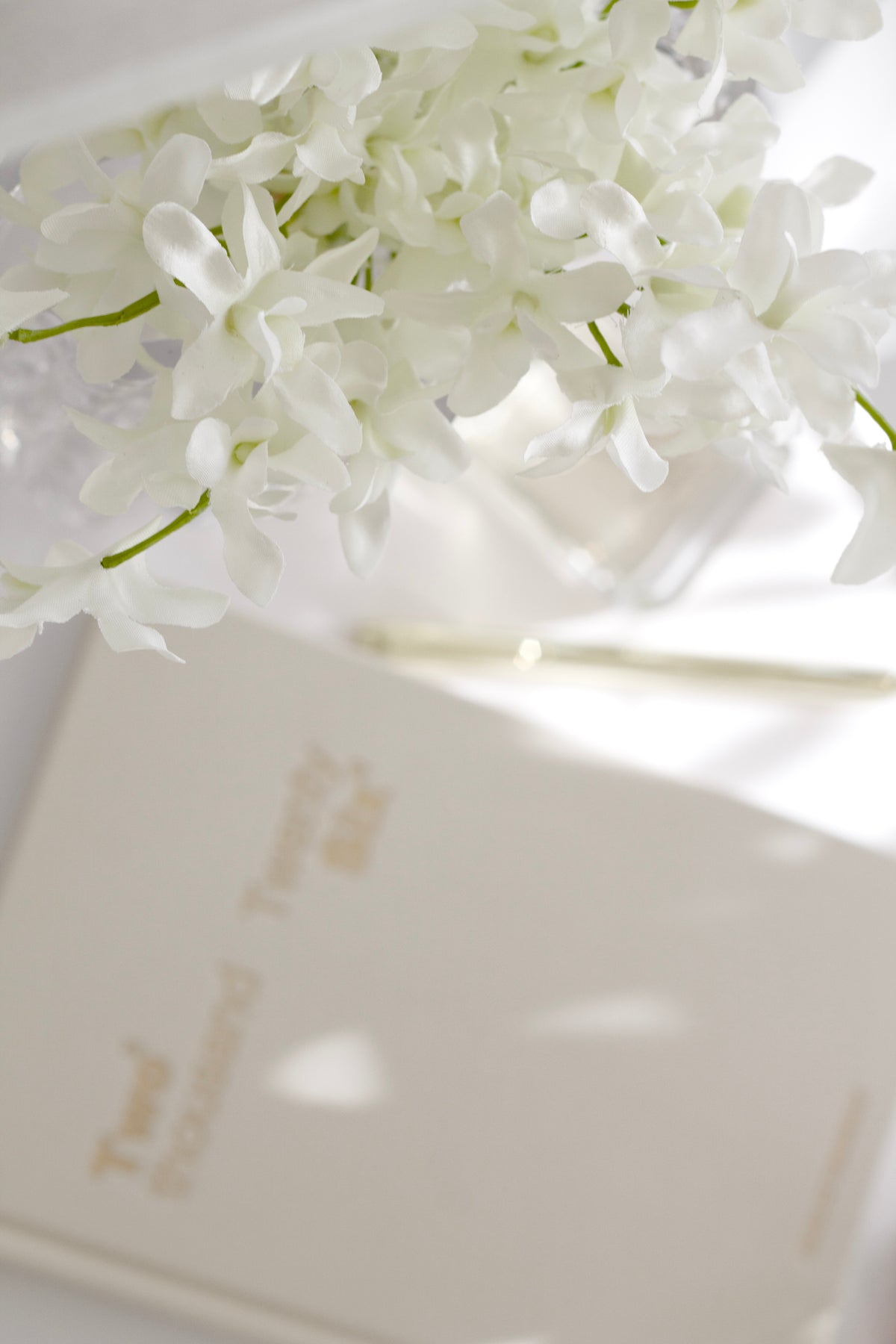 Faux white orchid stems laid on a pale linen surface
