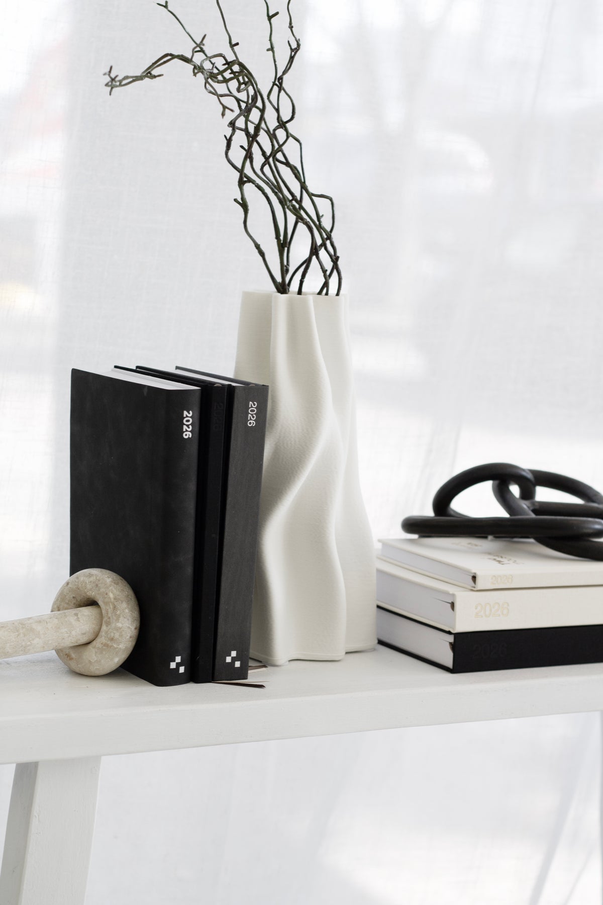 Anouk white vase with branches on a shelf beside black books and a small bowl