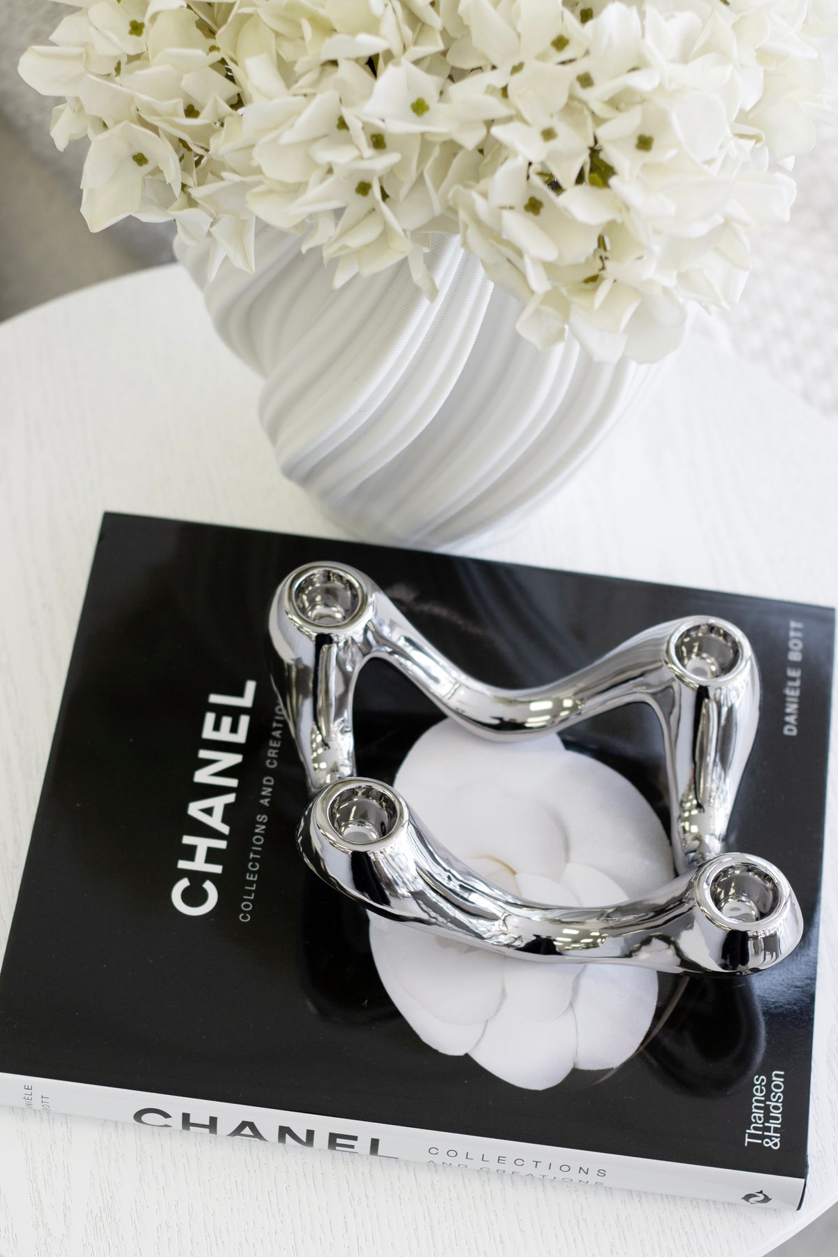 White Amelie fluted vase holding white hydrangeas on a stack of monochrome coffee table books