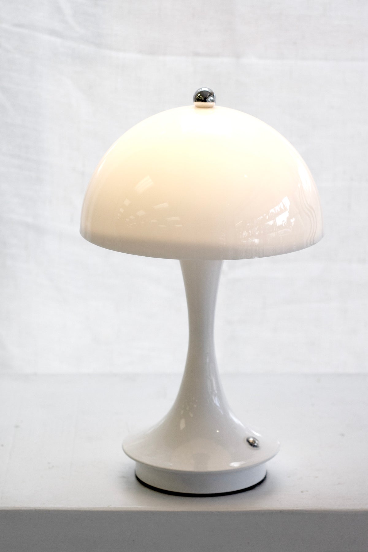 Close up of the white mushroom lamp lit, against a soft linen backdrop