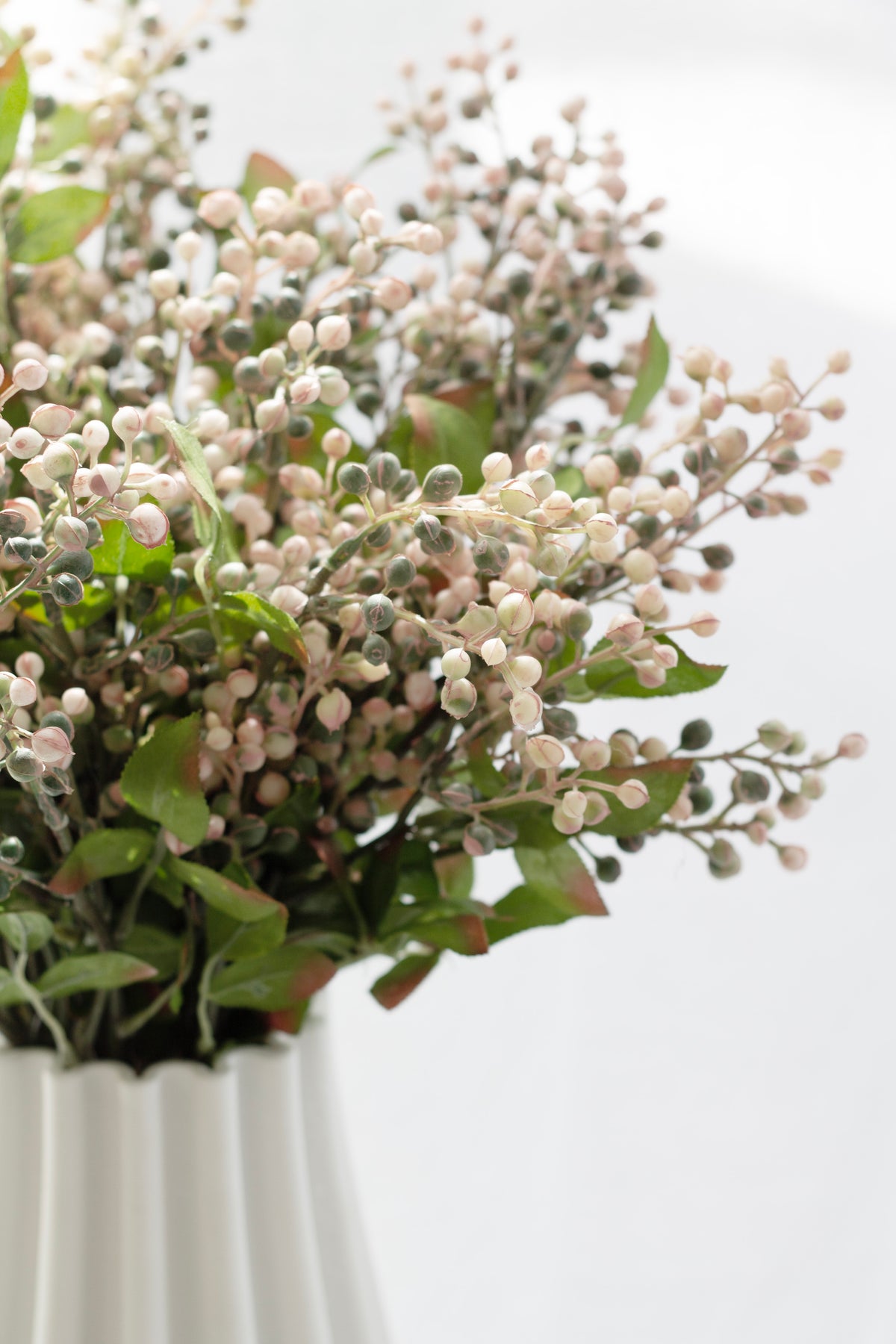 Cottage berry spray arranged in a white fluted vase, berries in cream and dusty pink