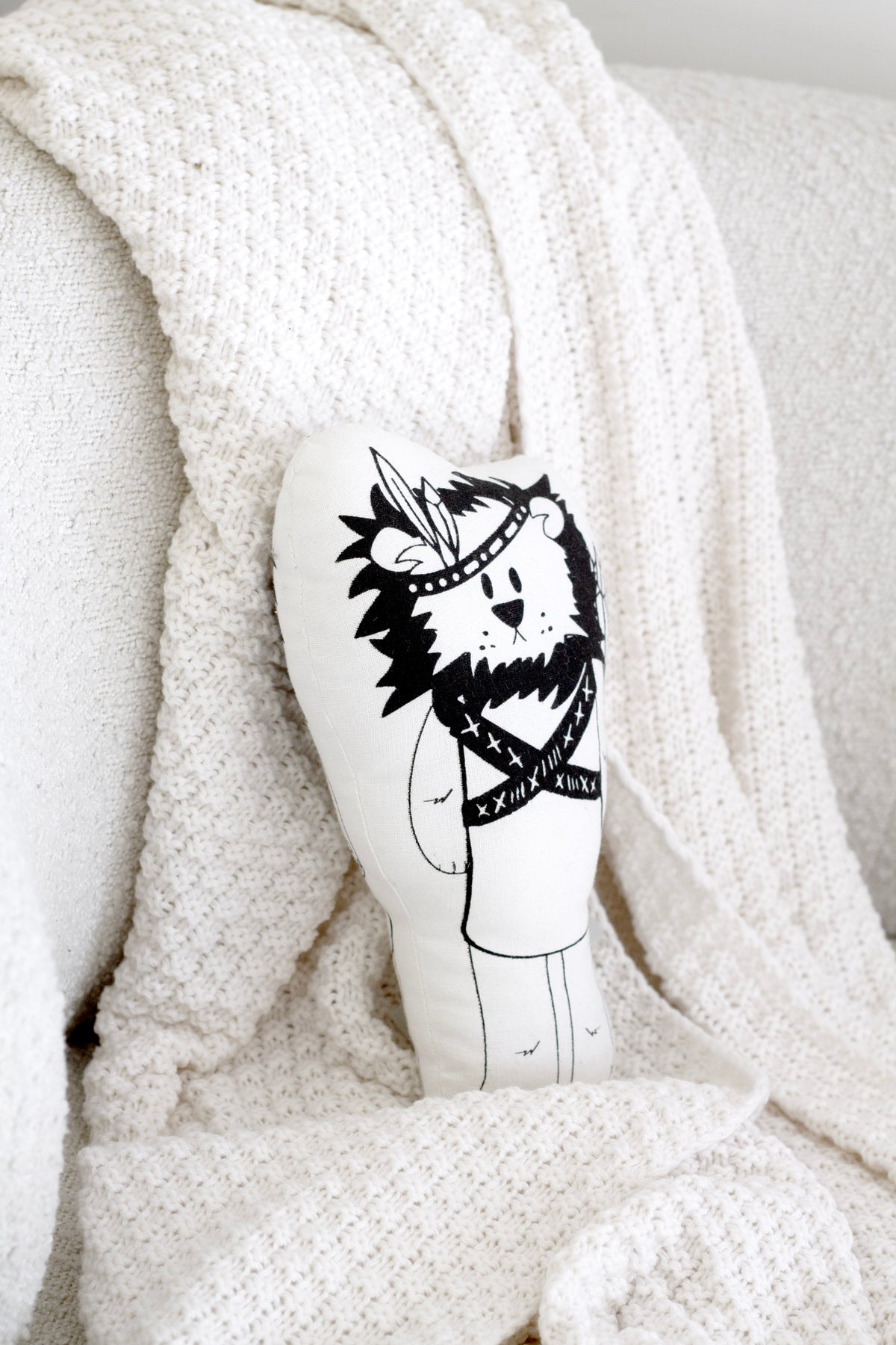 Liam the Lion soft toy on a white knitted throw