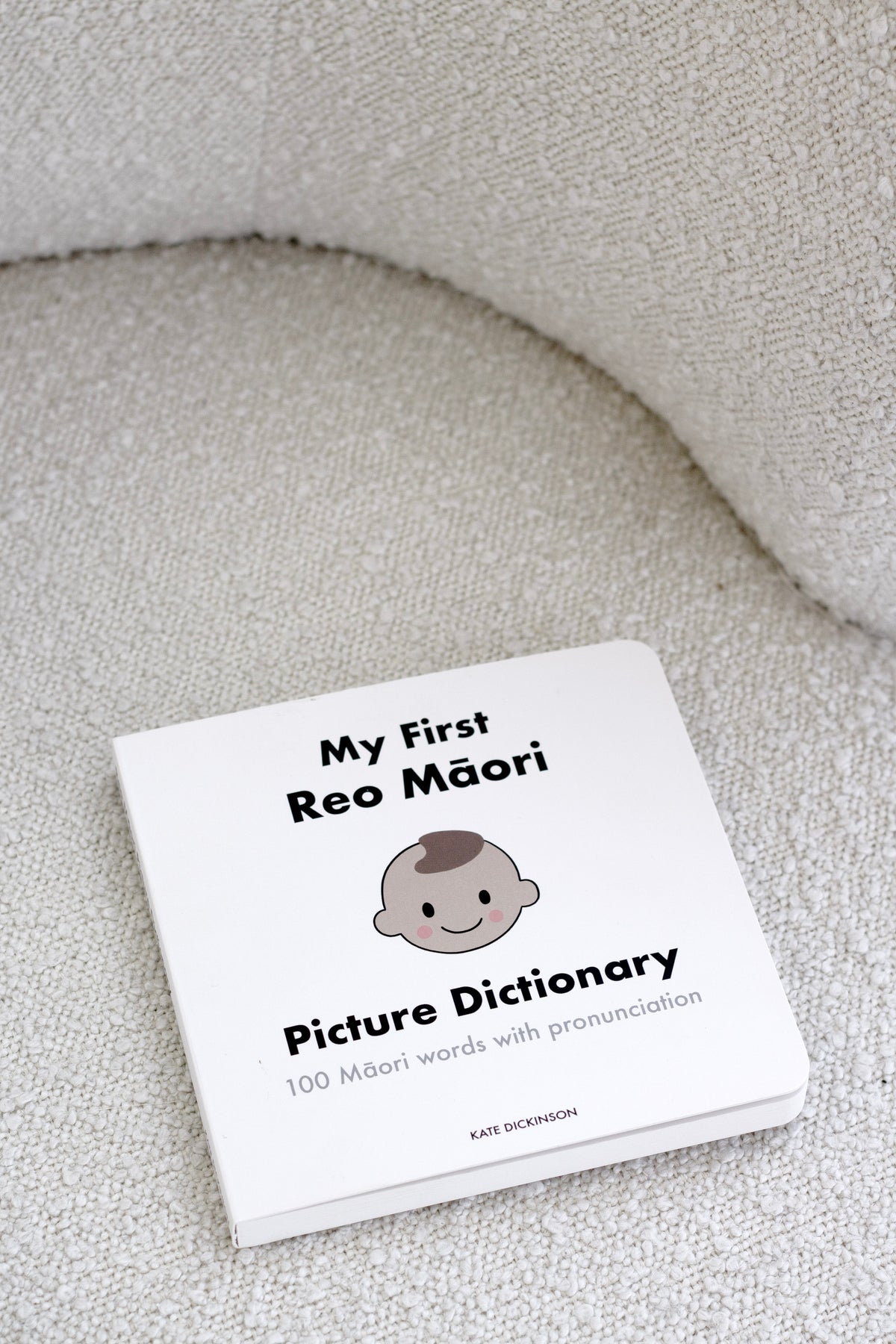 My First Reo Māori Picture Dictionary lying on a cream boucle chair seat