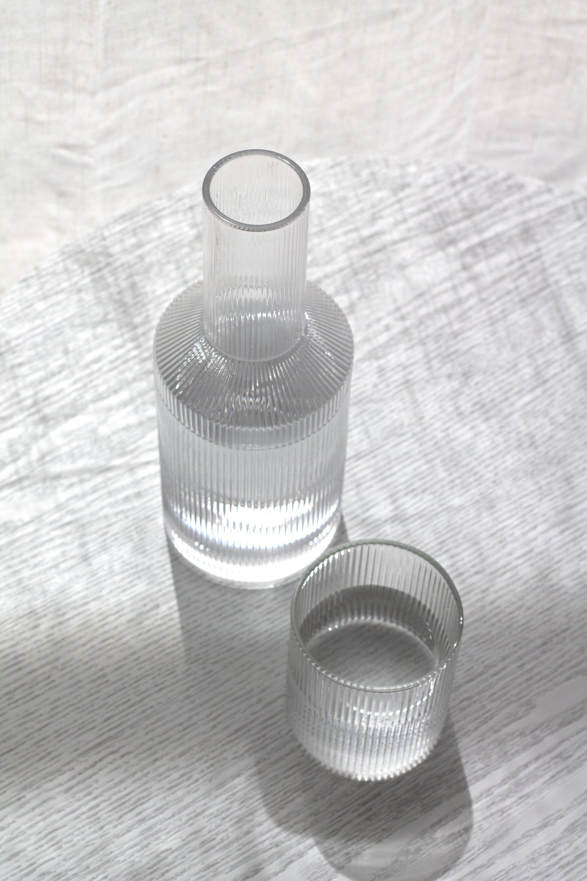 Fluted glass decanter with a matching tumbler resting on white linen