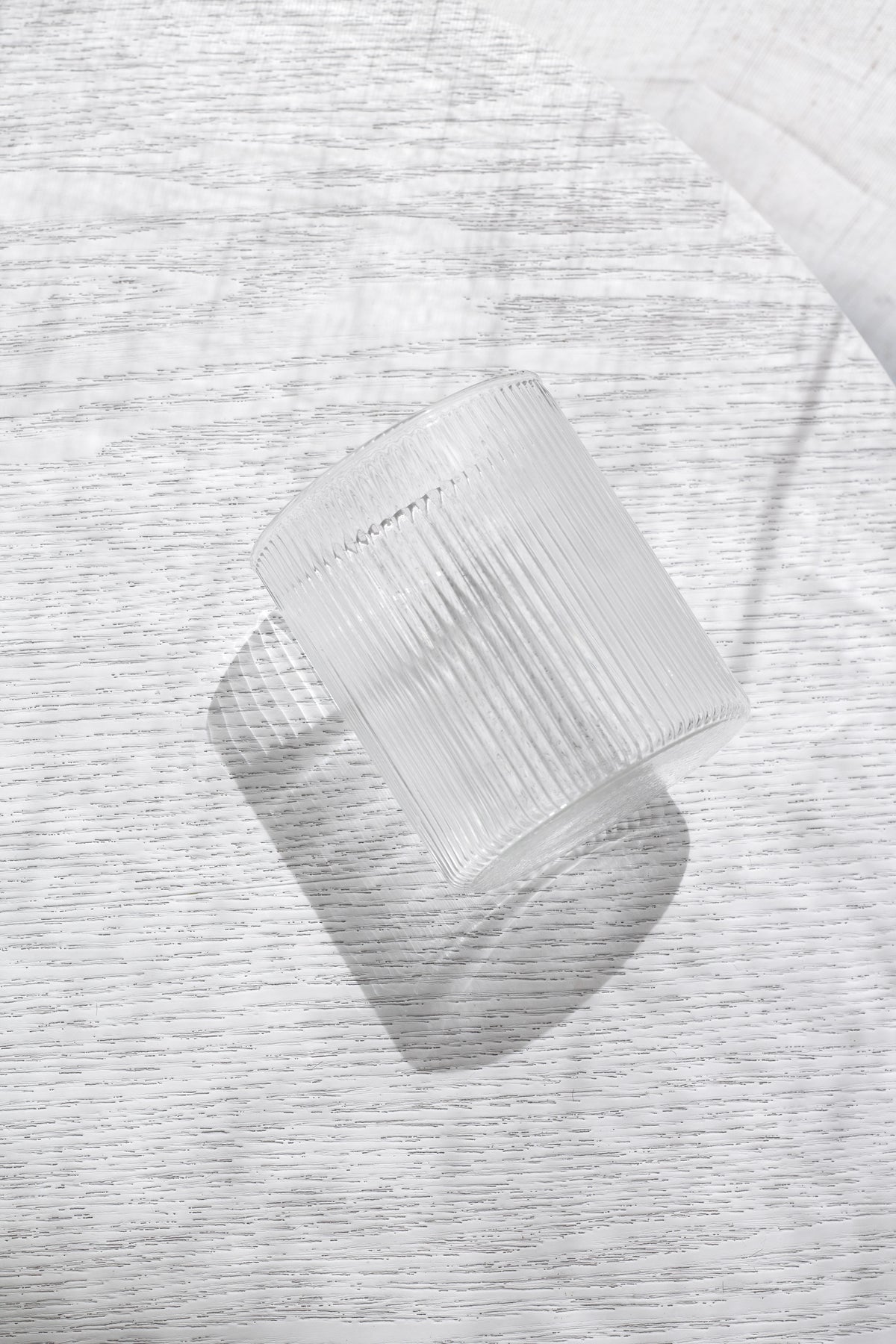 Fluted Amalfi glass lying on its side on white linen