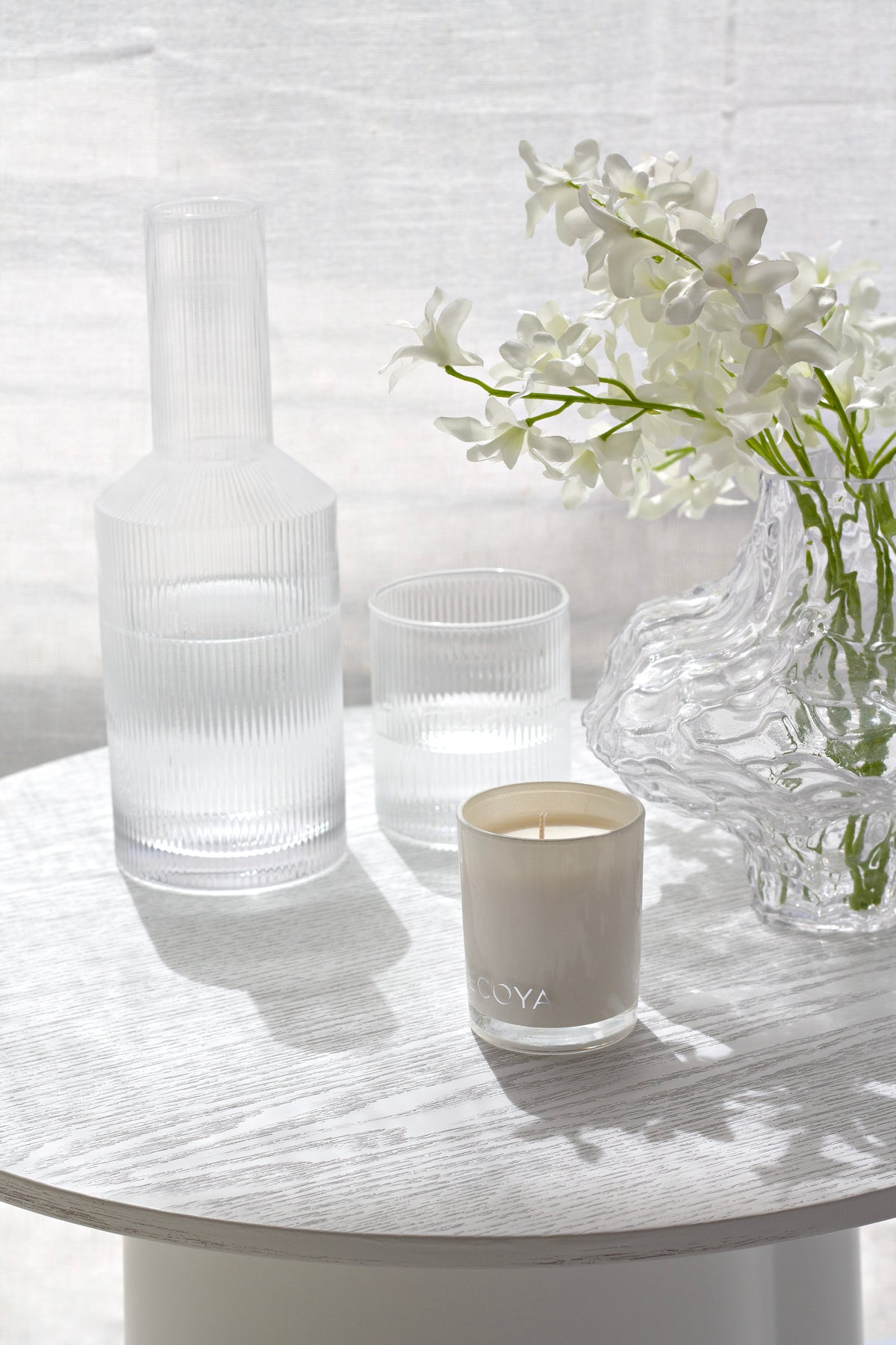 Amalfi decanter, glasses and a vase of white flowers on a round table
