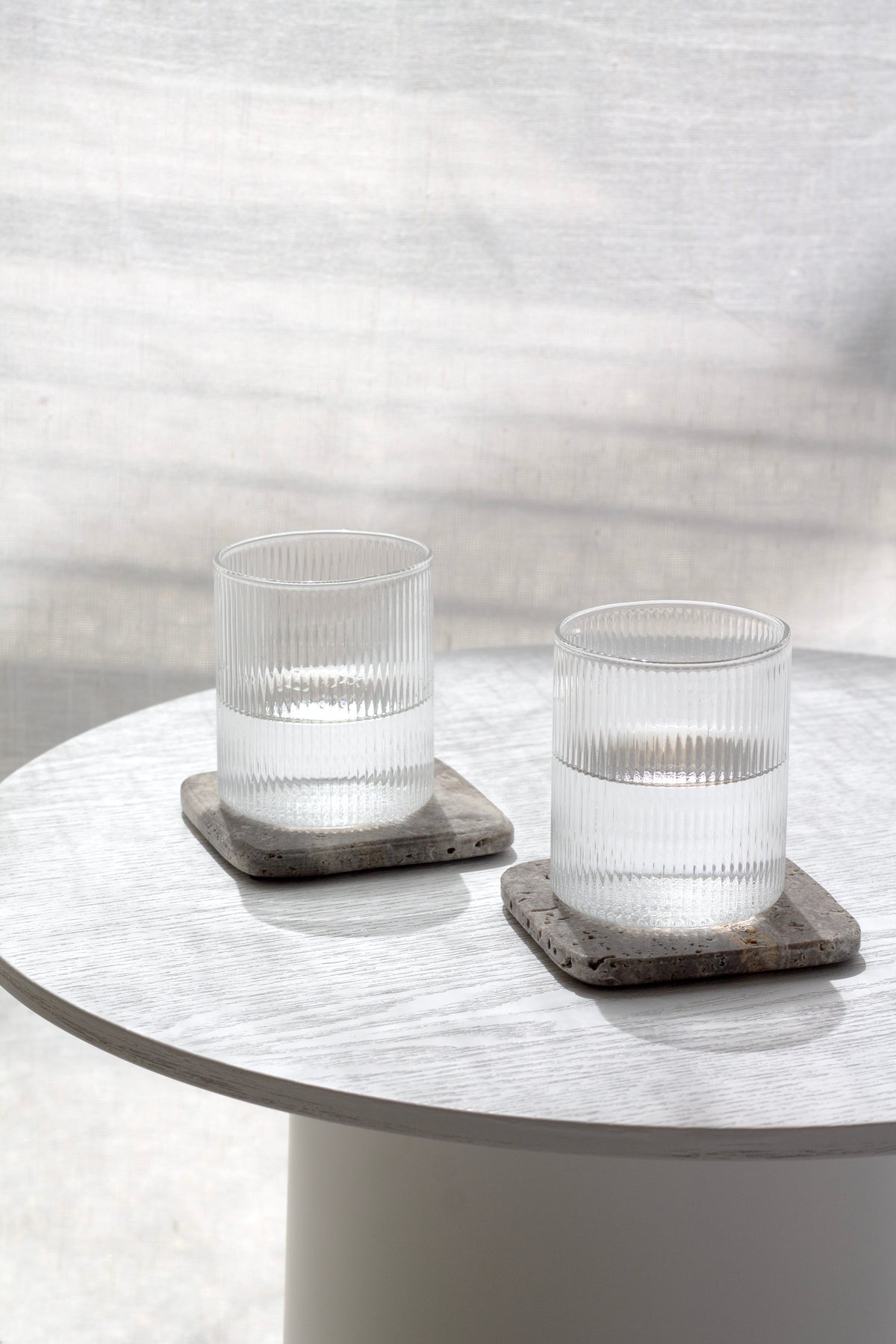 Two Amalfi glasses on dark stone coasters on a round white table