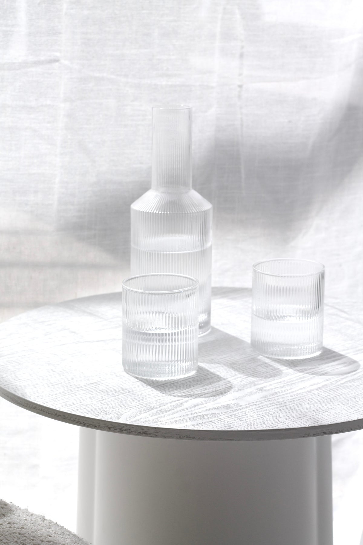 Side view of the Amalfi decanter and glass on a round white side table