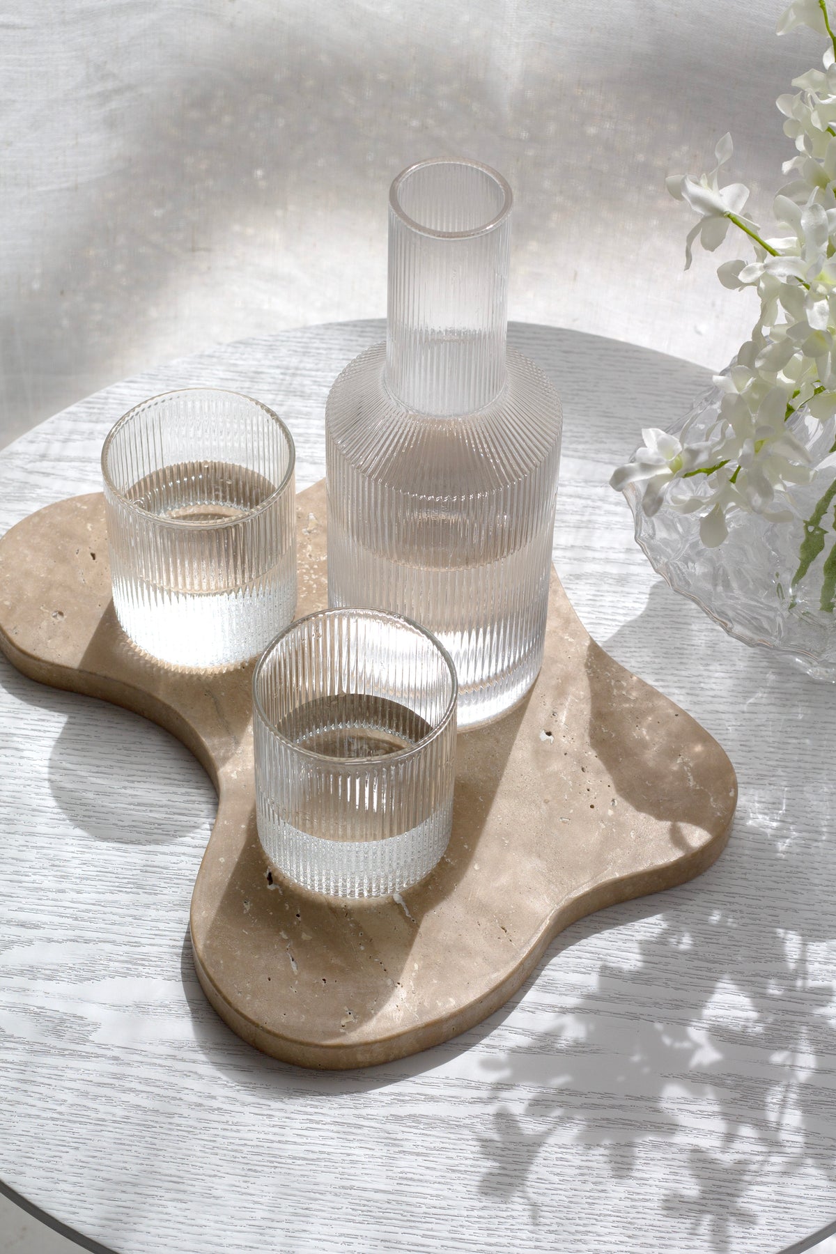 Top-down view of the Amalfi decanter and glasses on an organic timber tray with white flowers