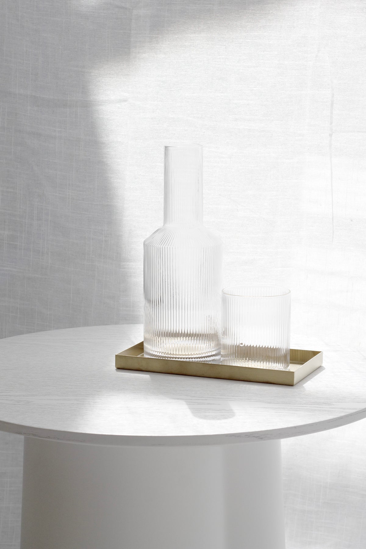 Amalfi decanter and glass on a brass tray atop a white side table