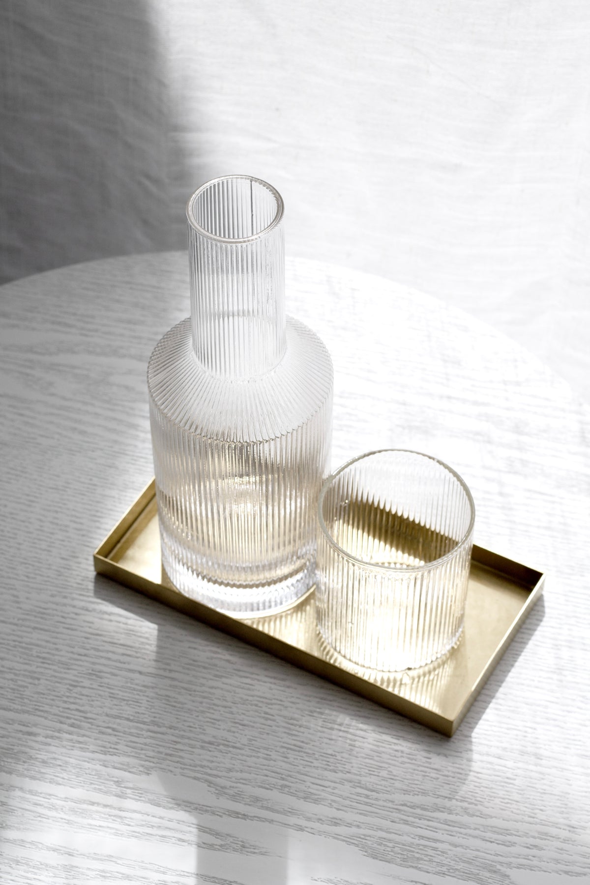 Amalfi decanter and fluted glass on a slim brass tray on a white table
