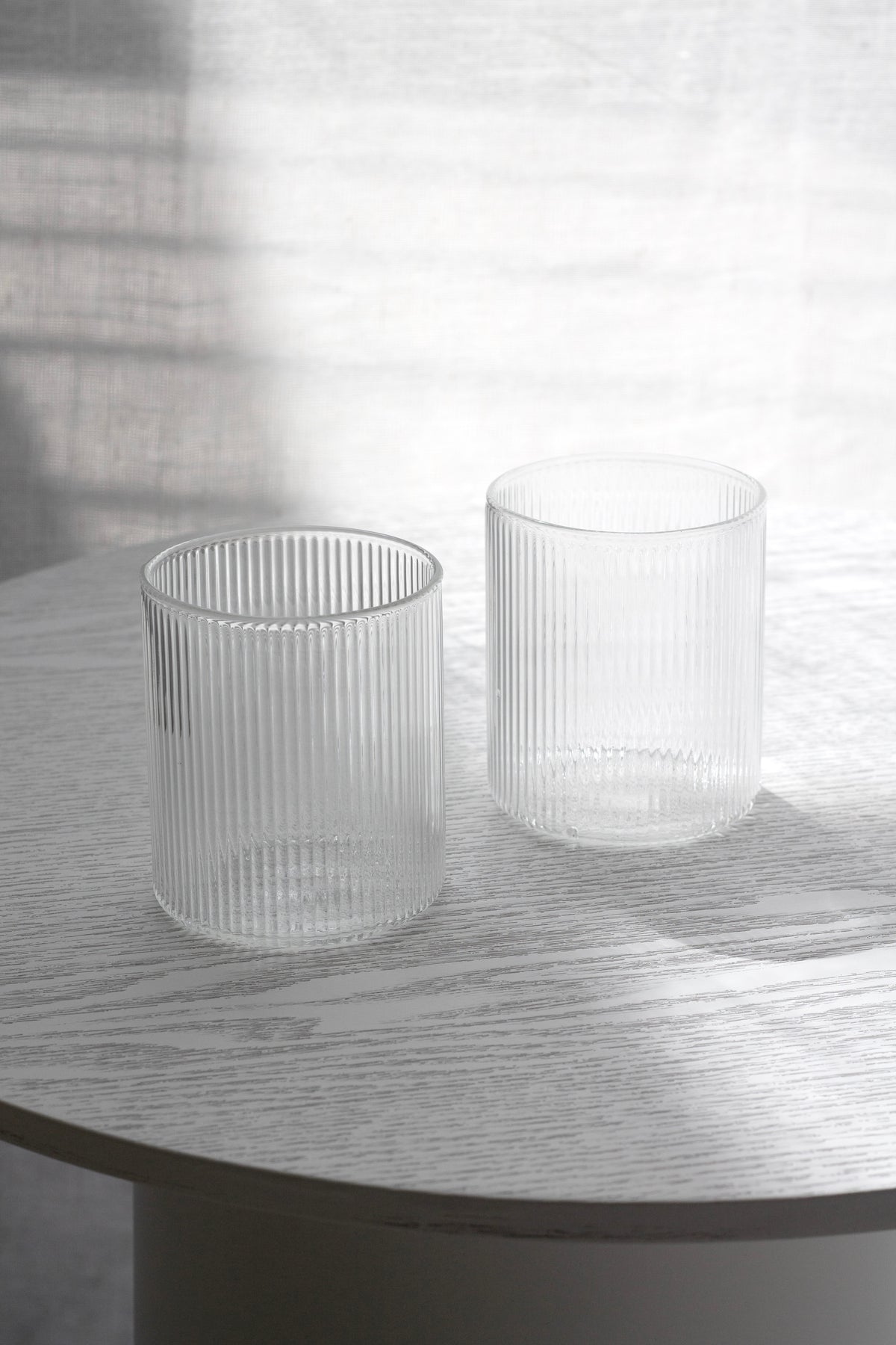 Two fluted Amalfi water glasses on a white table in soft window light