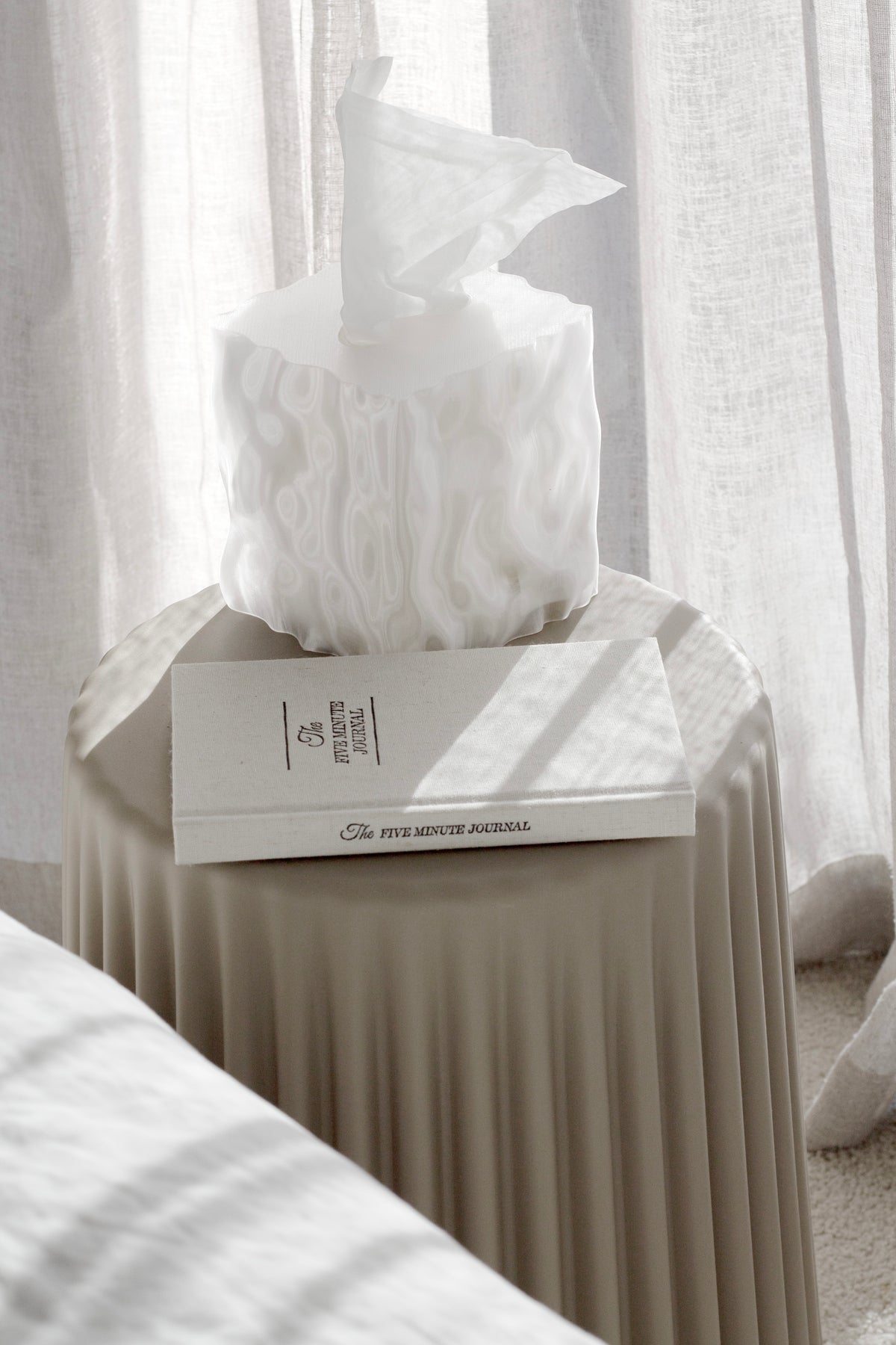 White Flow cover on a book atop a ribbed side table beside a bed