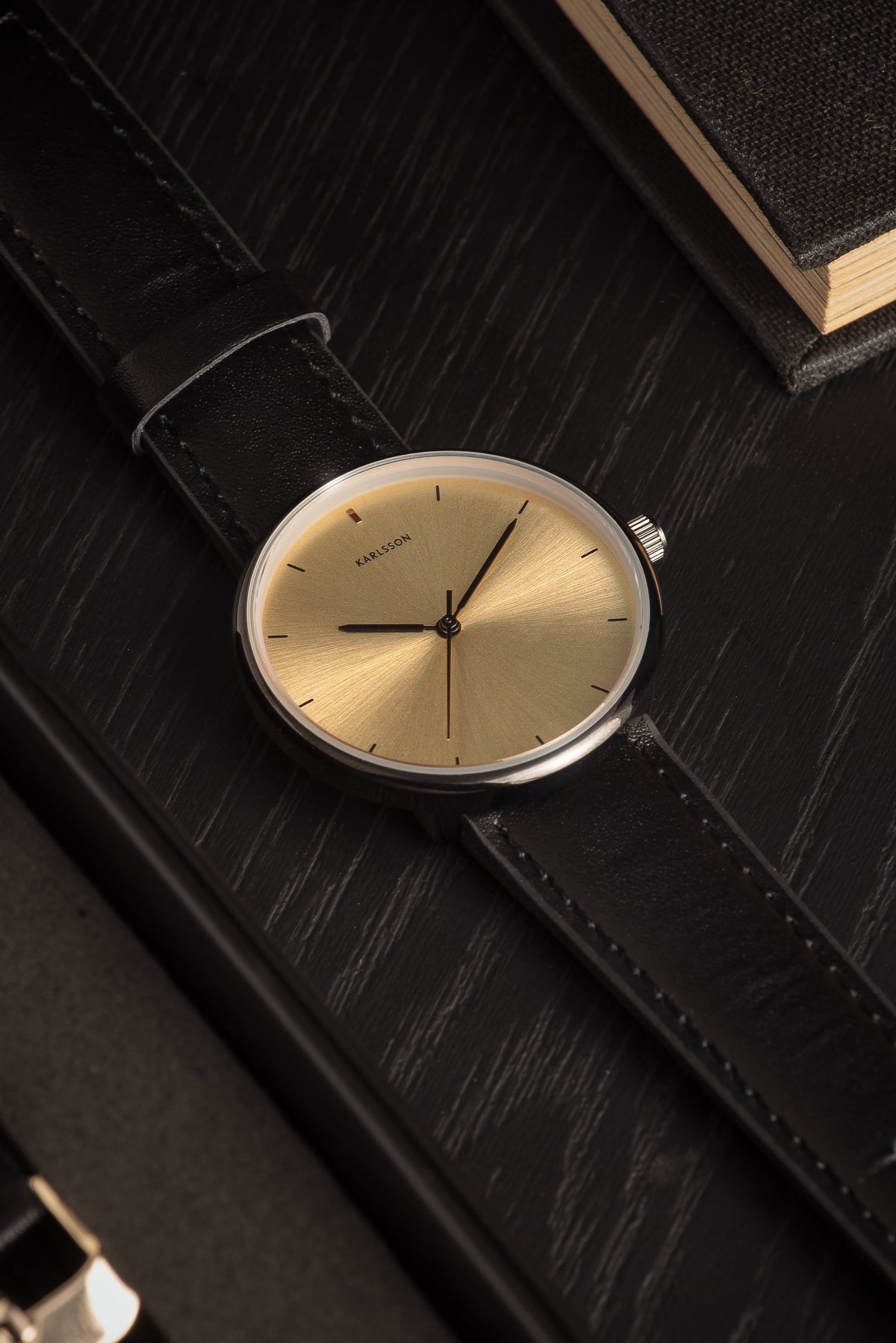 Karlsson Finesse watch lying unfastened on a dark textured surface