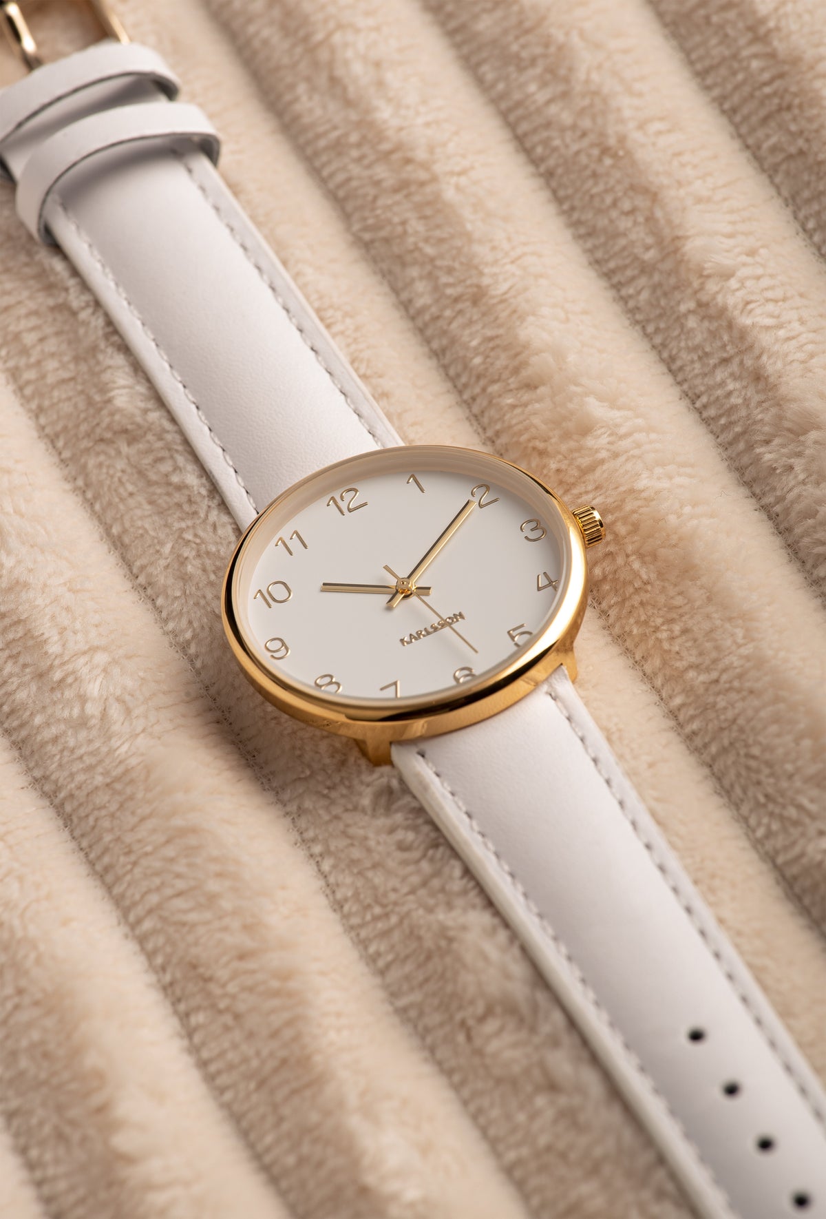 Karlsson Charm watch resting on soft beige textured fabric, shown at an angle