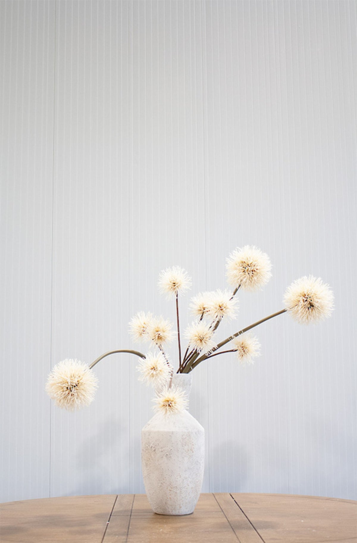 Natural brown dandelion sprays styled in a clear glass vase