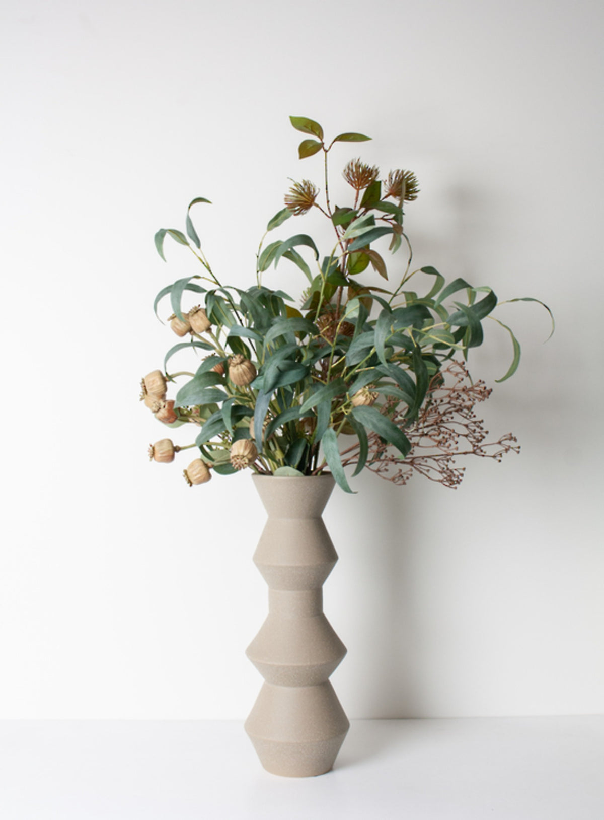 Grey-green eucalyptus spray bundle styled in a tall sculptural vase