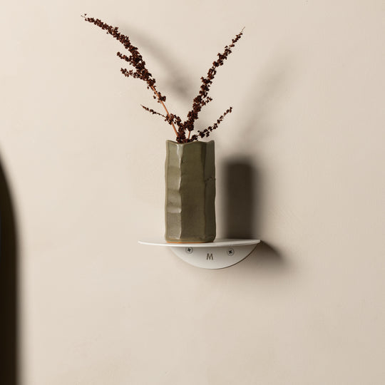 Small white FOLD Round Shelf holding an olive ceramic vase of dried stems