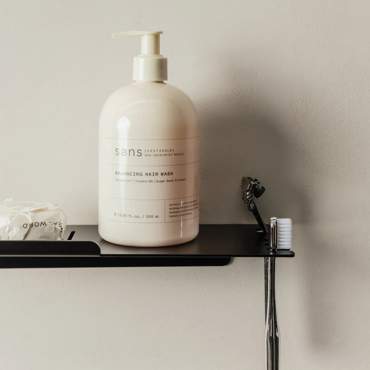 Black FOLD shower shelf holding a cream pump bottle and toothbrush