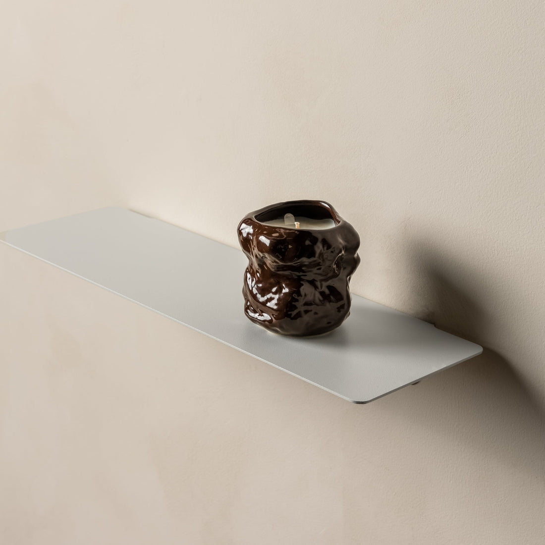 Angled view of a white FOLD Ledge with a dark ceramic vase