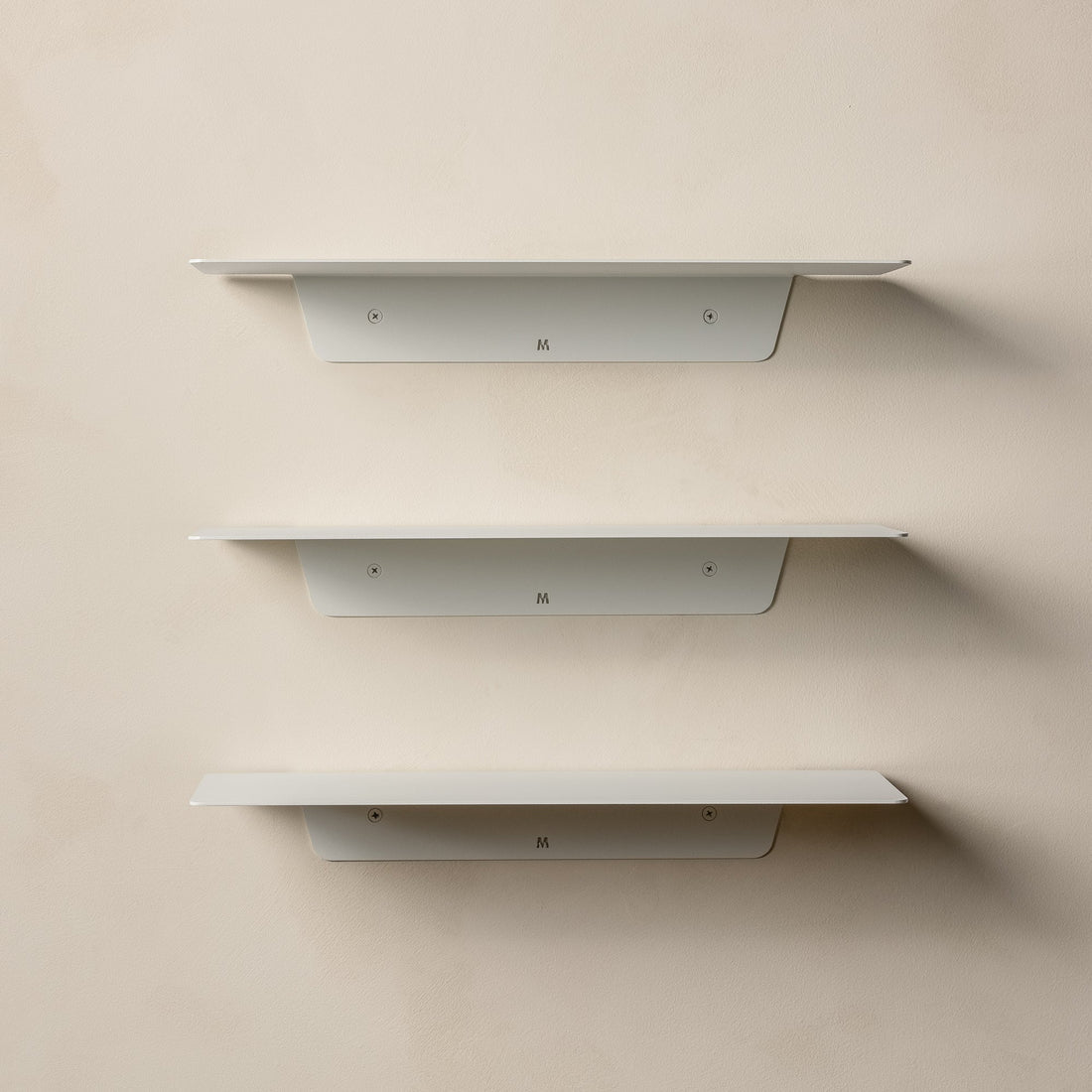 Three empty white FOLD Ledges stacked on a beige wall