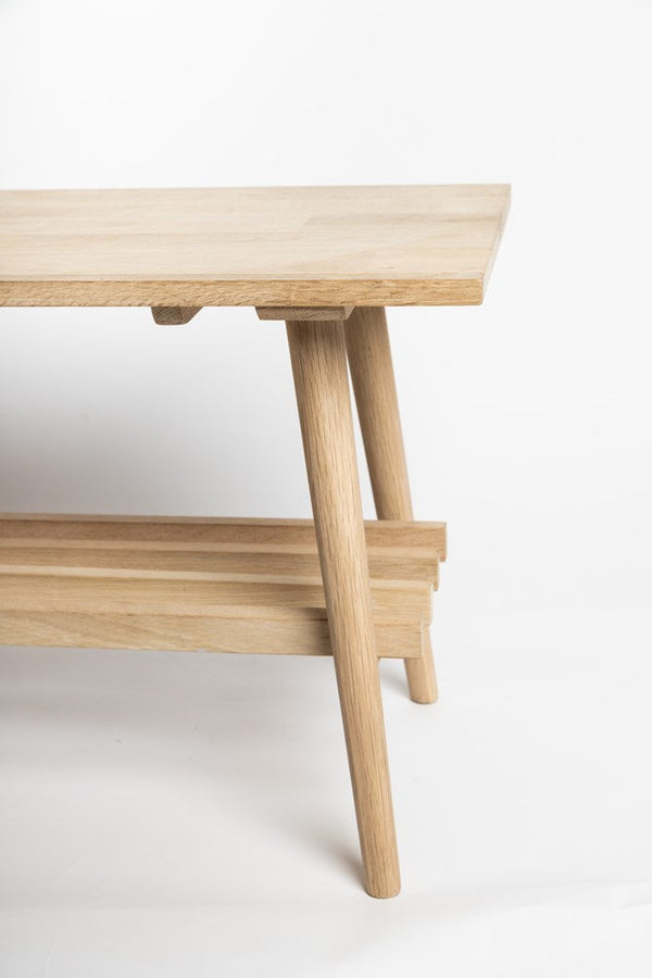 A Ned Collections David Long Bench with a wooden shelf, known for its density and strength.
