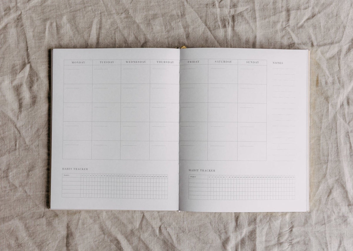 Open monthly calendar spread of the YOU. journal on linen, with blank date grids and space for monthly notes