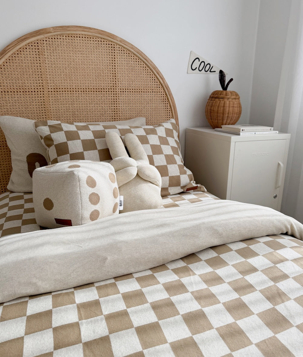 Kids bed with a rattan headboard, khaki gingham duvet cover and a dice cushion