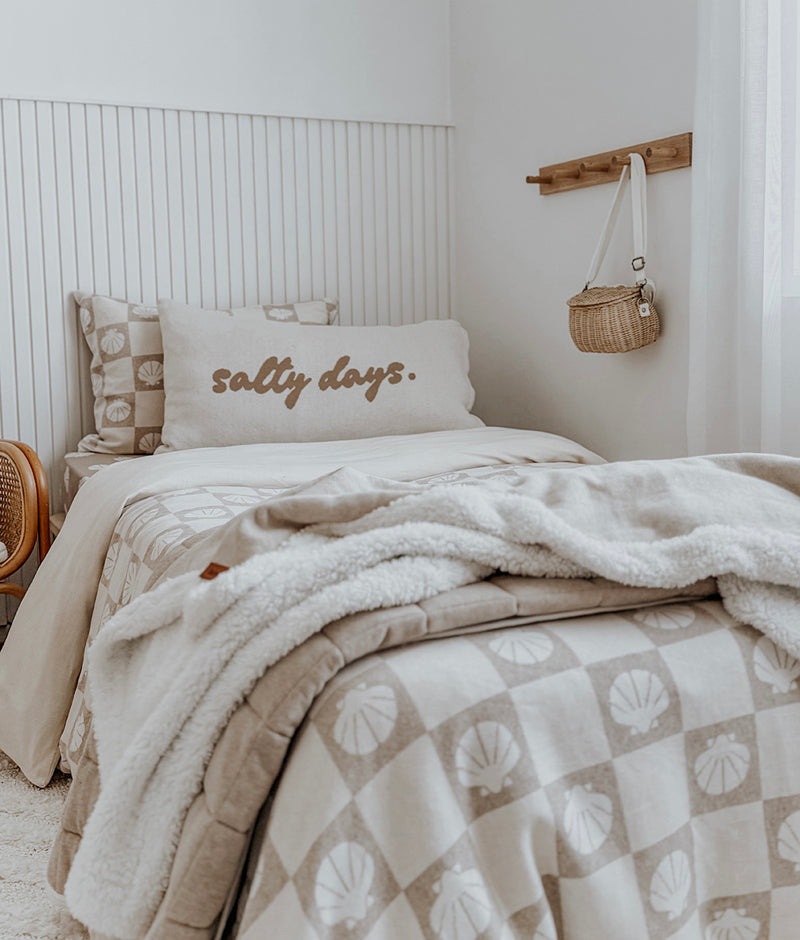 Salty Days pillowcase on a kids bed with a shell check quilt, Sherpa throw and panelled wall