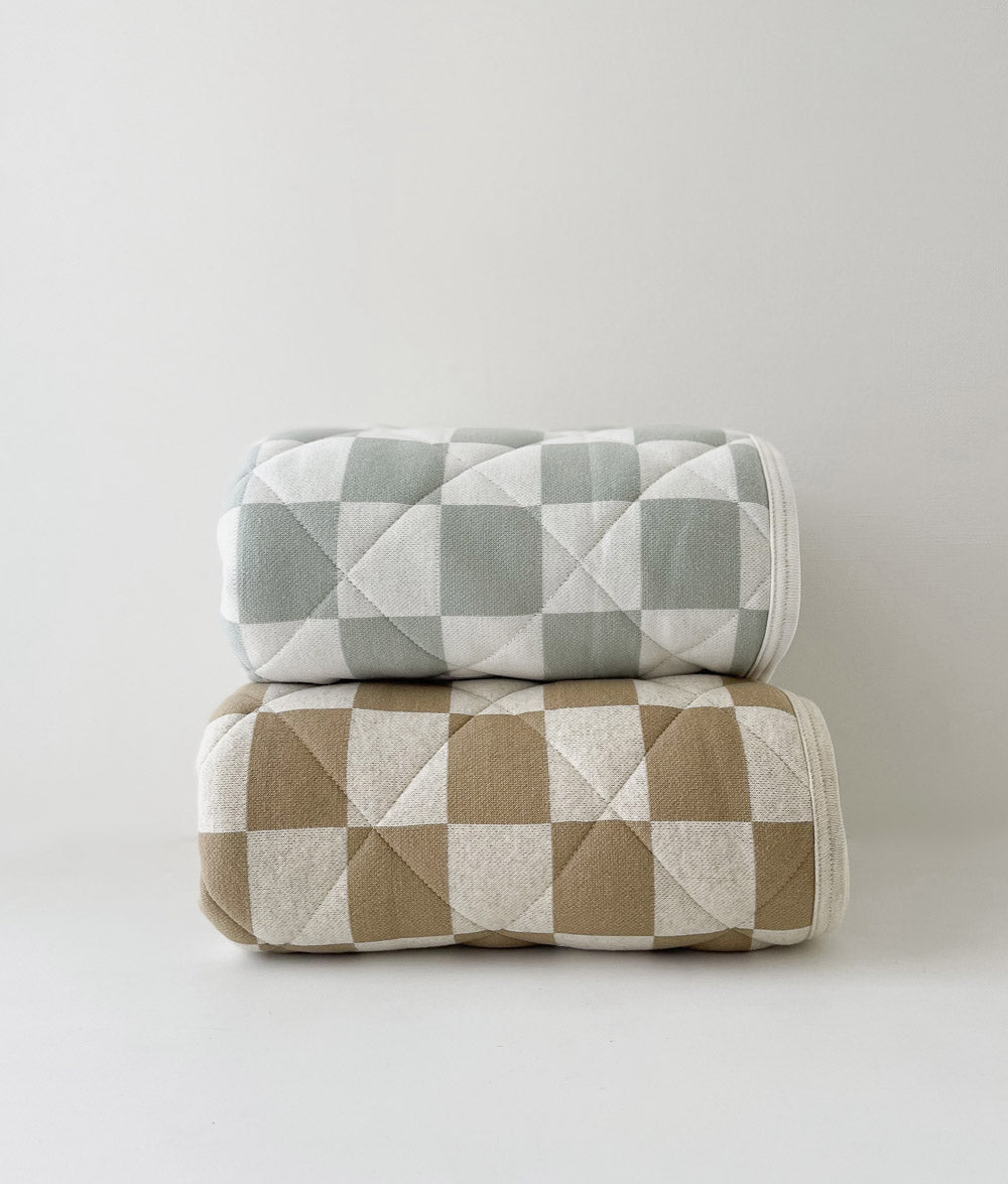 Rolled Sage Gingham quilt stacked on a rolled Khaki Gingham quilt on a white backdrop