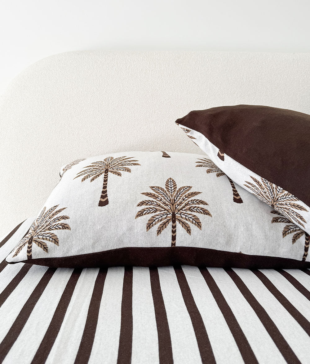 Palm print cushion and chocolate euro layered on the Sundown Stripe striped fitted sheet