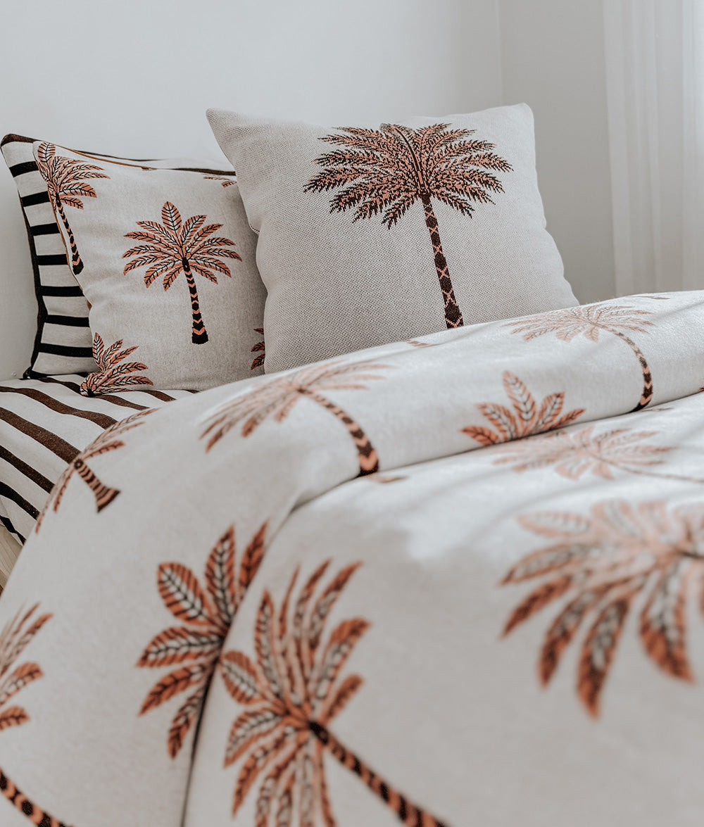 Two kids beds in palm print bedding with Sundown Stripe pillowcases and cushions