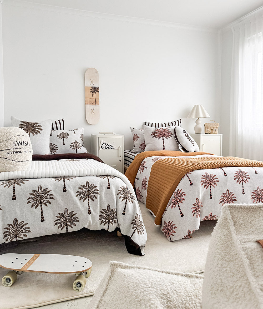 Wide view of a shared kids room with palm print bedding and the basketball sherpa cushion