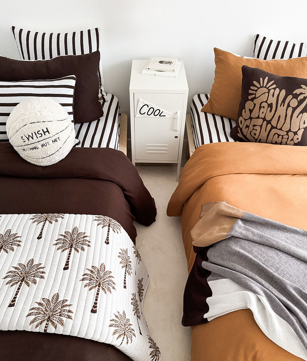 Kids room with two beds in chocolate and tobacco bedding, Sundown Stripe pillows and a basketball cushion