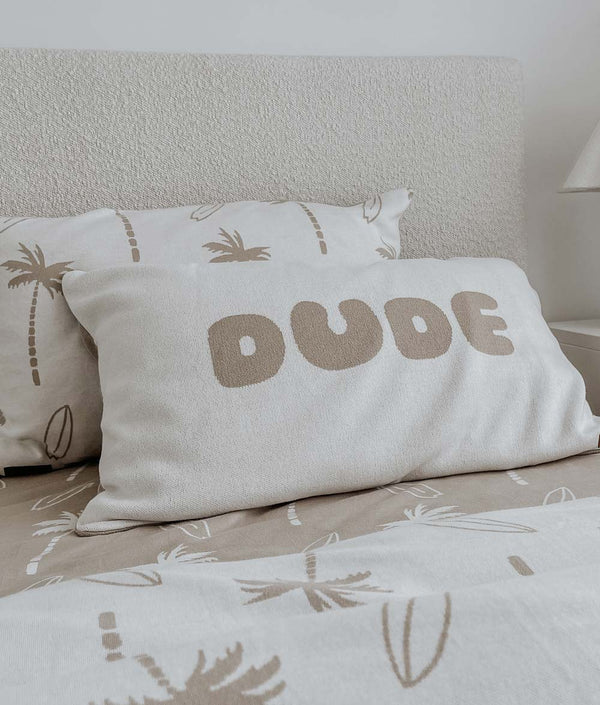 Surfing Palm kids cotton pillowcase behind a DUDE pillowcase on a bed made up in sand Surfing Palm