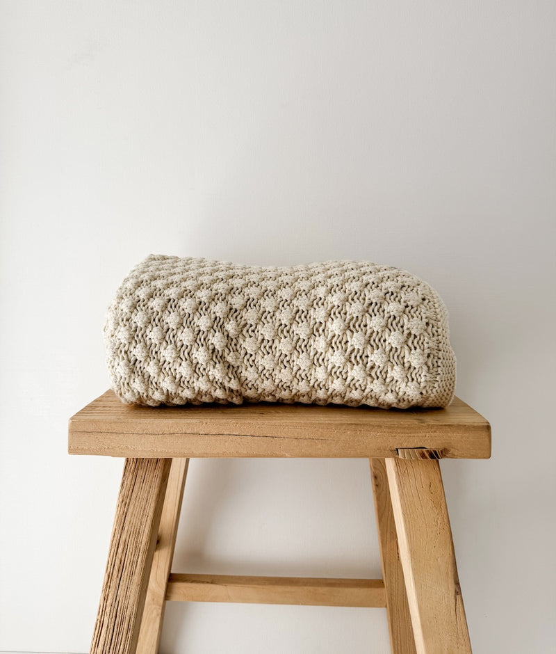 Close view of the folded Bone Popcorn lounge throw showing its raised bobble knit in bone cotton