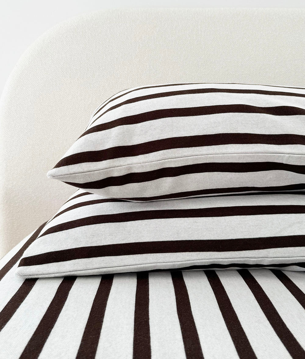 Striped euro and standard pillow stacked on the Sundown Stripe jersey cotton fitted sheet