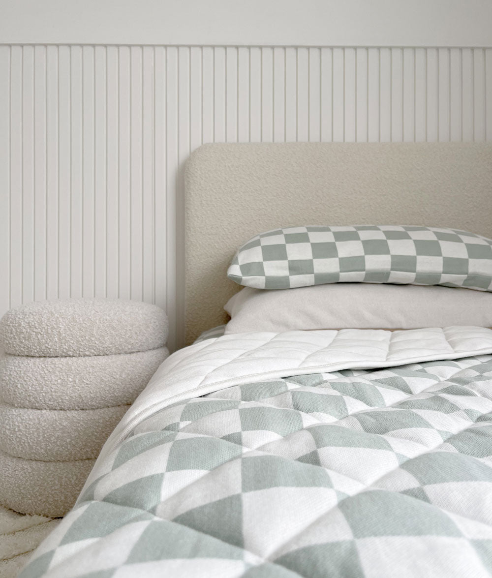 Sage Gingham reversible quilt on a boucle bed against white panelling with a matching pillowcase