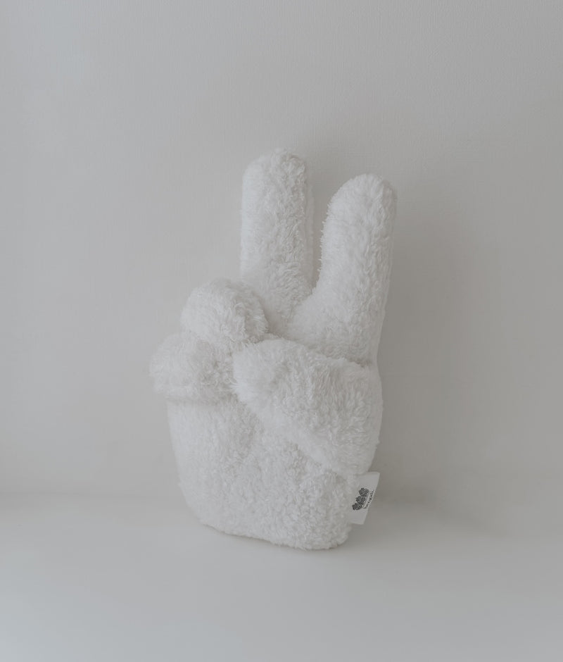 Ivory Peace Sherpa kids cushion in a peace-sign hand shape, photographed on its own against white