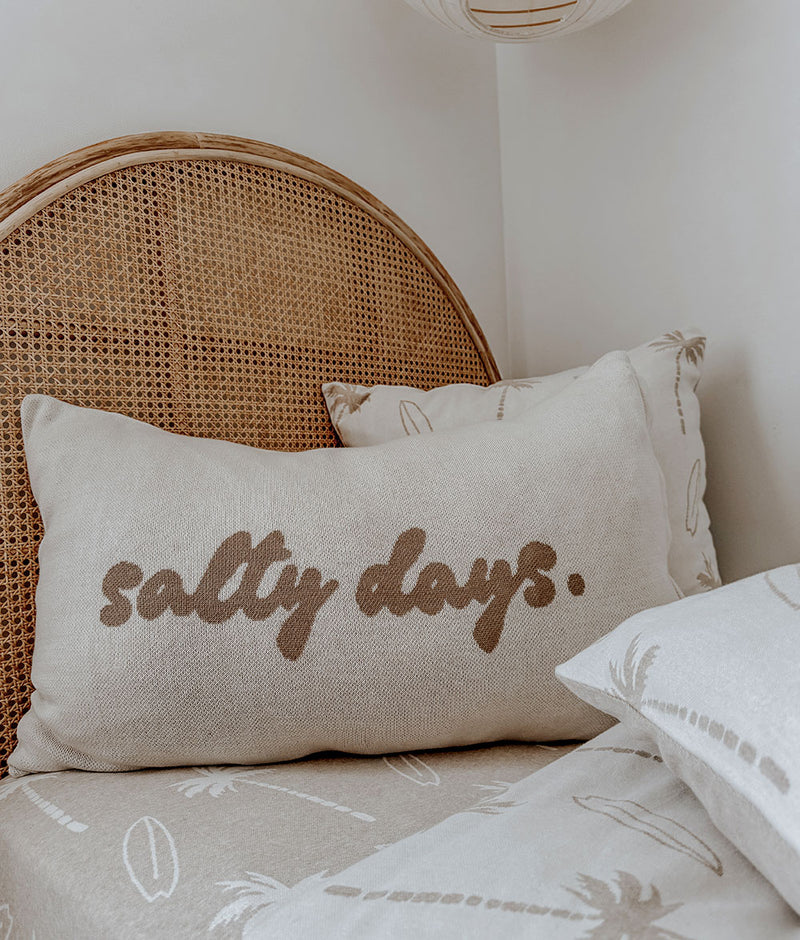 Salty Days cotton pillowcase against a rattan bedhead on Surfing Palm bedding
