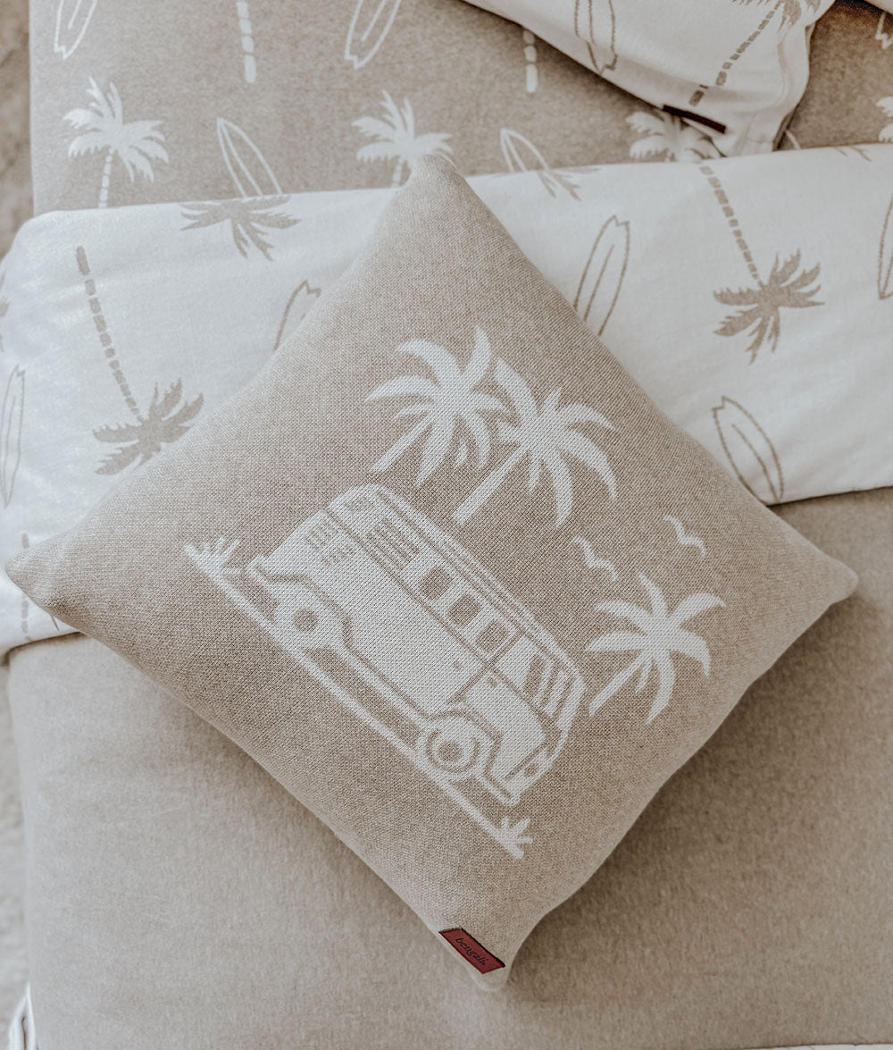 Dune campervan cushion resting against palm print pillows on the dune bedding