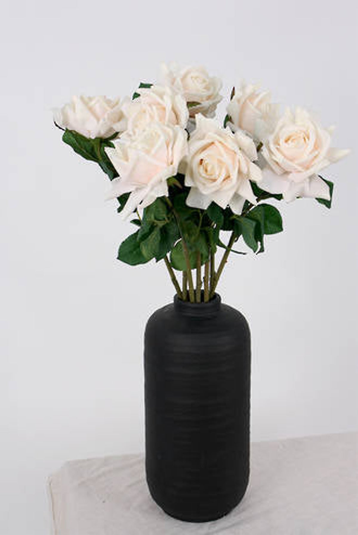 Peach roses in a black ribbed vase