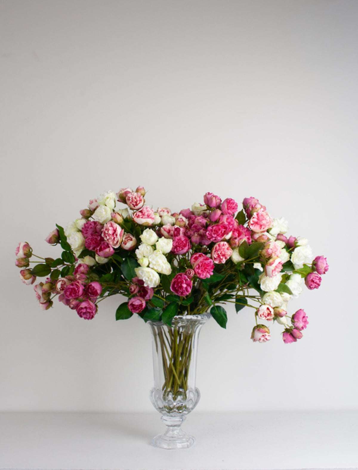 Large bunch of pink and white spray roses in a clear cut glass vase